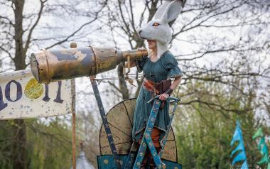 Performer with rabbit head costume stood by giant telescope during performance at Egg Rolling.