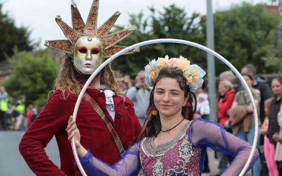 Man in costume with gold carnival mask and woman carrying hoop during 2017 Caribbean Carnival.