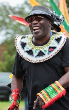 Man wearing decorated collar and cuffs laughing during Caribbean Carnival parade 2017.