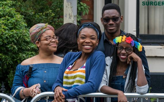 Spectators of 2017 Caribbean Carnival parade smiling for camera.