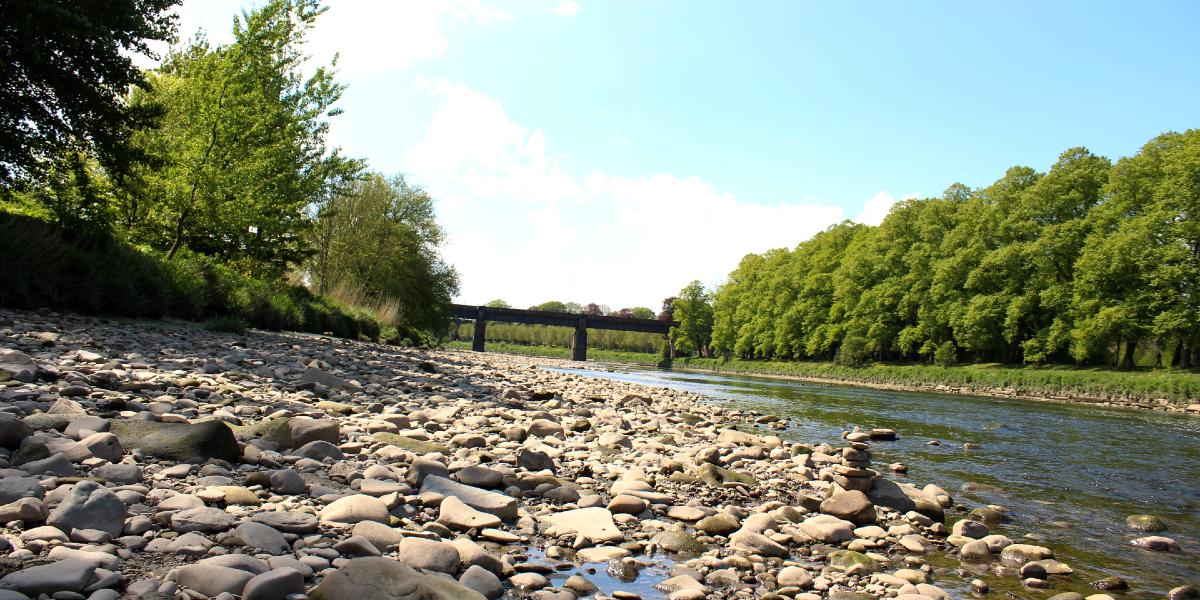 Stone beach of River Ribble with view of river and bank in Avenham Park.