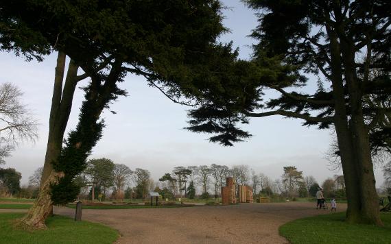 Father and child walking along Grange Park pathway with trees on either side.