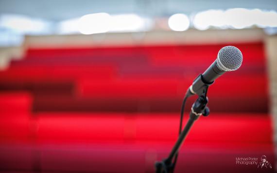 Microphone in foreground with MET red tiered seating in background.