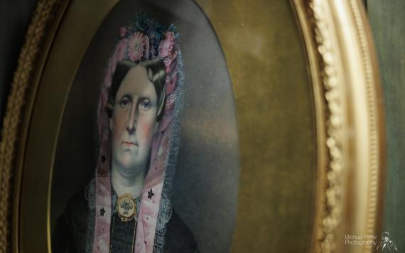 Close up of painting of woman in round gold frame inside Harris storage.