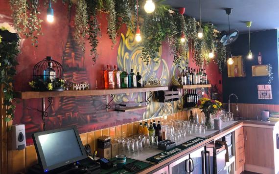 Itsy's Street Food drinks bar with hanging plants and a wall mural of a Thailand temple