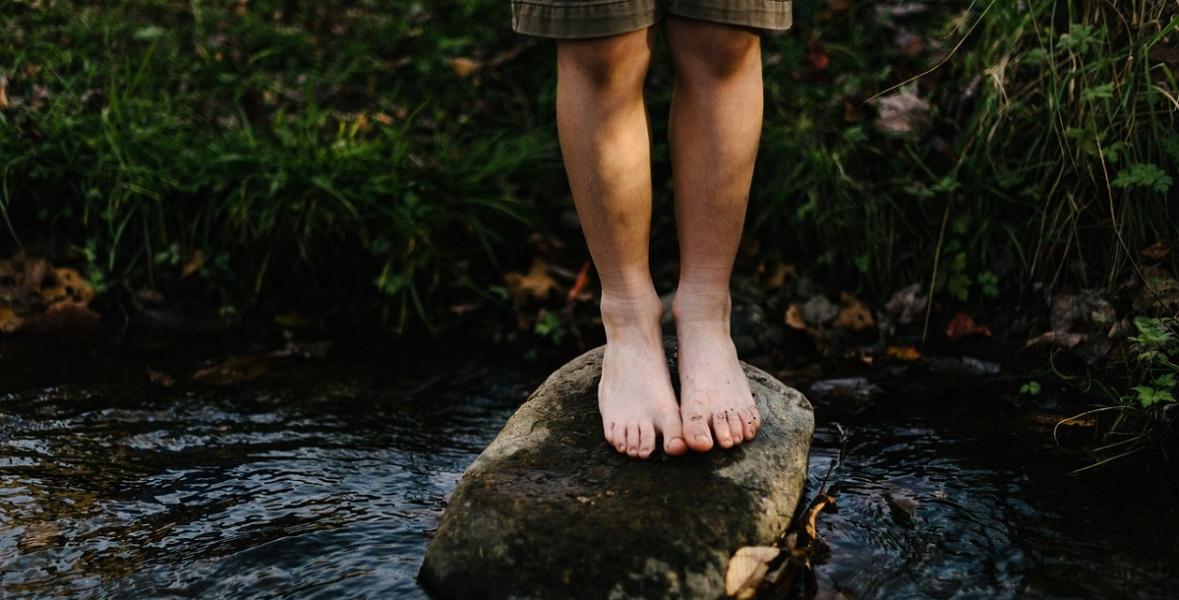 Child on stepping stone in shallow stream