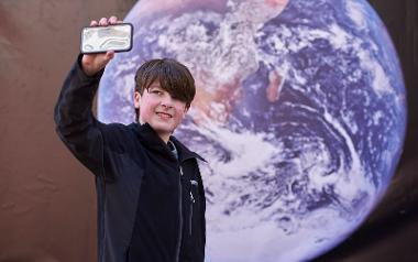 Child taking selfie with photograph of earth in background