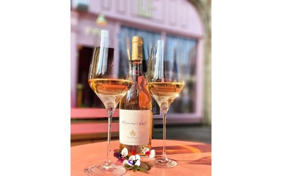 Two glasses and a bottle of wine on a table with small flowers outside Le Fleur Bar