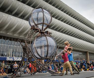 Performers doing acrobatics next to Timeless installation