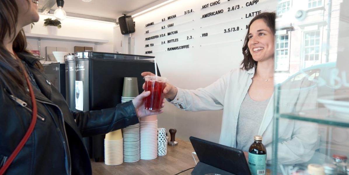 Cafe assistant serving customer a drink to go 