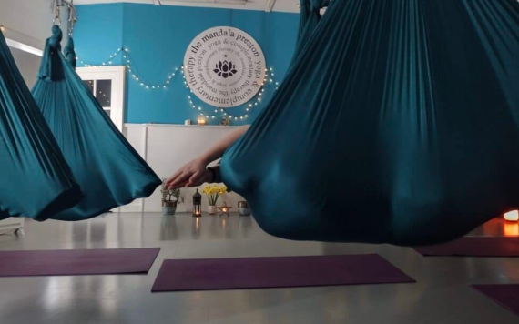 People wrapped in hanging cloth hammocks as part of a meditation activity