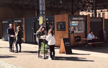 Different people enjoying coffee whilst stood at tables outside Jonah's Coffee