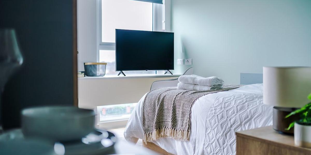 City Studios bedroom with TV in front of a well lit window