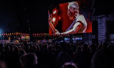 Sting shown on screen performing on stage