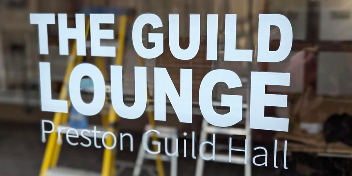 A sign on a glass window saying The Guild Lounge