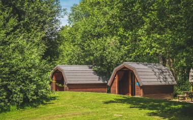 Two of the Bowland Lakes Camping Pods under green trees