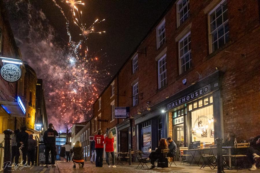 A group of people watching a firework display outside Winckley Ale House