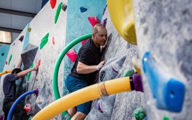 A man concentrating as he climbs up an indoor climbing wall