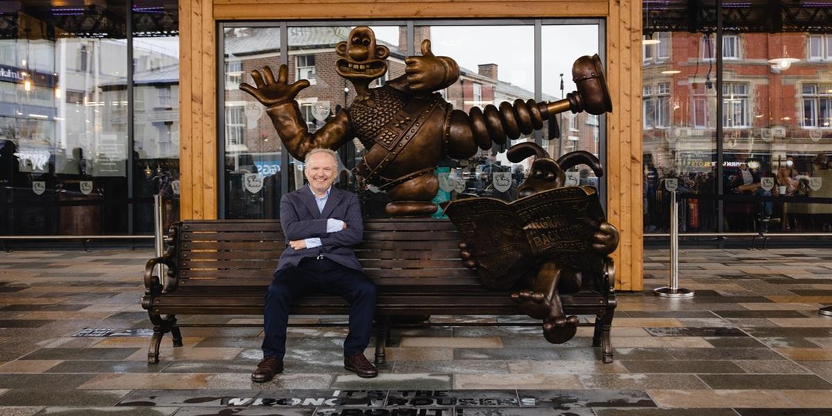 Nick Park sat on the Wallace and Grommit bench  in Preston in Spetember 2021.