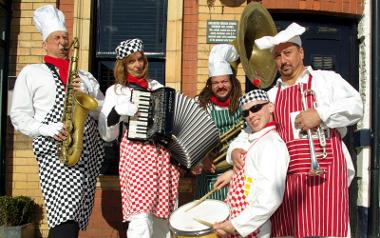 The SkiBand wearing chef clothing holding instruments posing for a photo