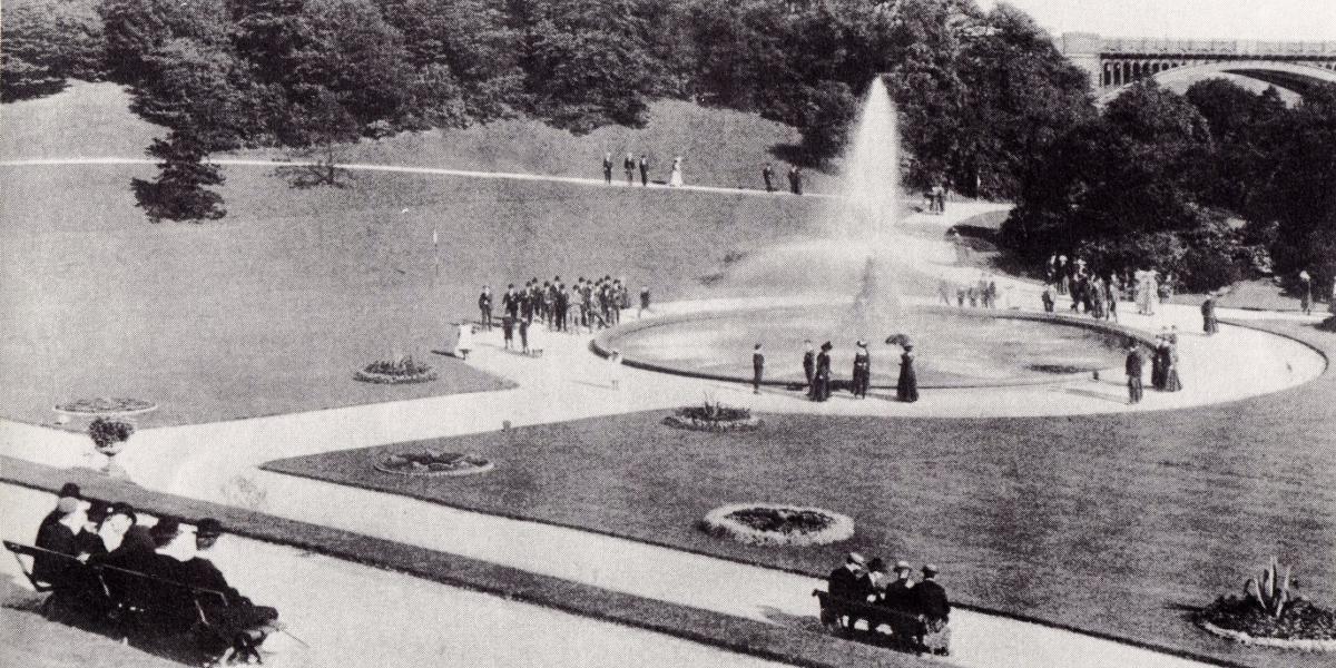Main image: Vintage black and white photograph of men and women relaxing around the fountain in Miller Park. Vintage black and white photograph of men and women wearing Victorian attire relaxing around the fountain in Miller Park.