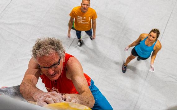 Two climbers watching man on climbing wall in Boulder UK.