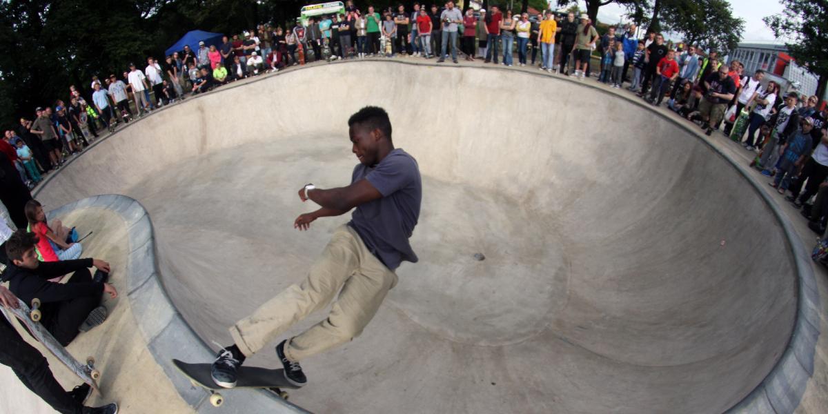 Boy skateboarding at Moor Park Skatepark with crowd watching.