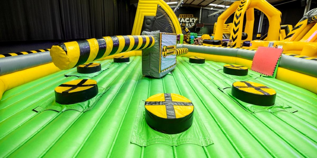 Main image: View of Wacky World inflatable theme park. Inflatable wipeout zone with other inflatables in the background.