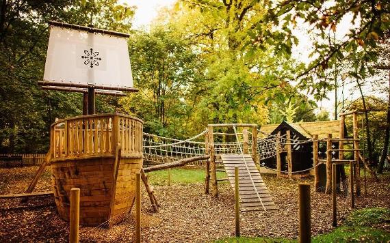 Wooden ship and miniature Samlesbury Hall structure inside children's play area.