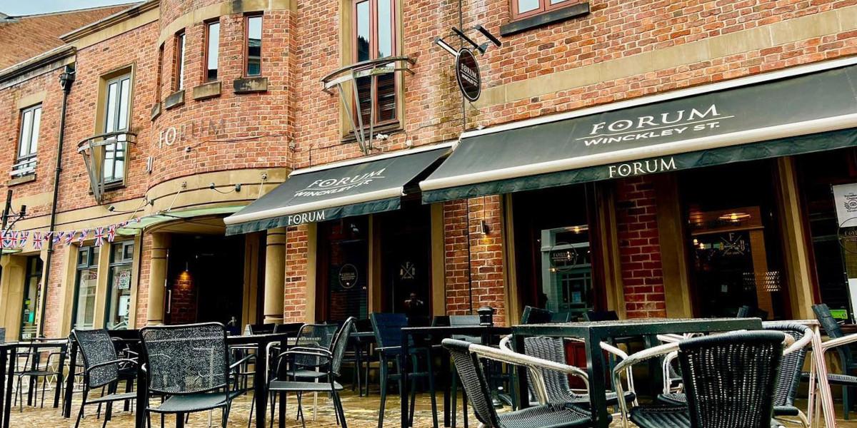 Looking at the outside entrance to Forum Bar and Kitchen with tables and chairs