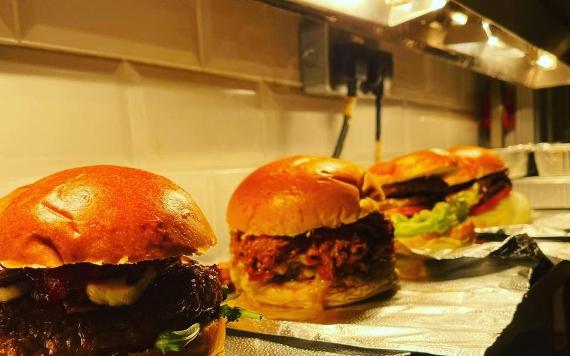 Beef burgers in a row inside Wings & Beer Co. kitchen.