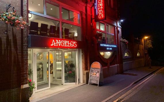 Angelos exterior lit up with red neon at night.