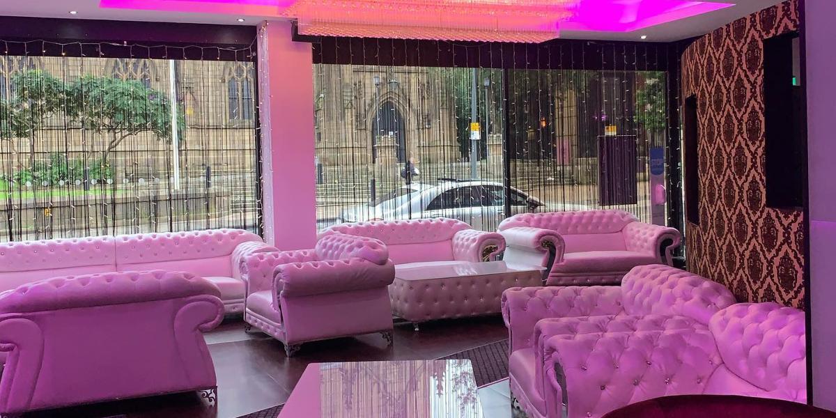 Main image: East Z East Preston's waiting area, lit up in pink with white sofas. East Z East Preston's waiting area, lit up in pink with white sofas.