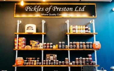 Pickles of Preston sign above shelves of preserves.