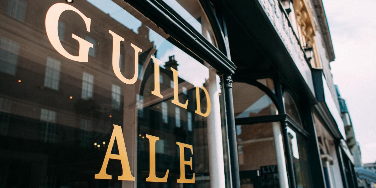 Guild Ale House lettering on front window of pub.