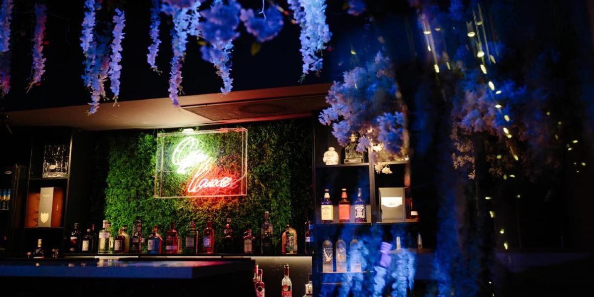 Main image: Review bar decorated with neon sign and fake plants. Review bar decorated with neon sign and fake plants.