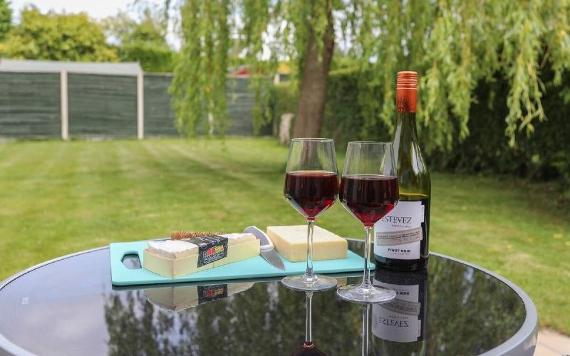 Two glasses of red wine and cheese selection in large garden at Bedzzz accommodation.