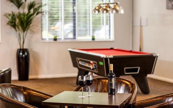 Pool table and glasses of wine on table in Ibis' lounge area.