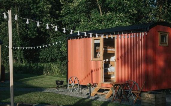 Red shepherd hut decorated with string lights.