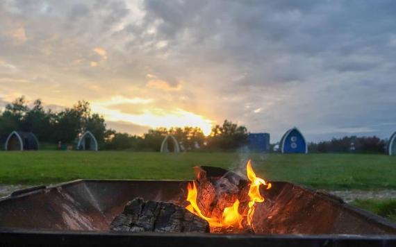 Fire pit with Stanley Villa camping pods in the background.