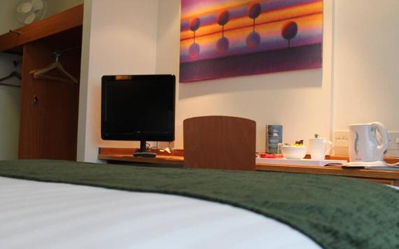 Foot of hotel bed and desk with tv inside Villa Express hotel room.