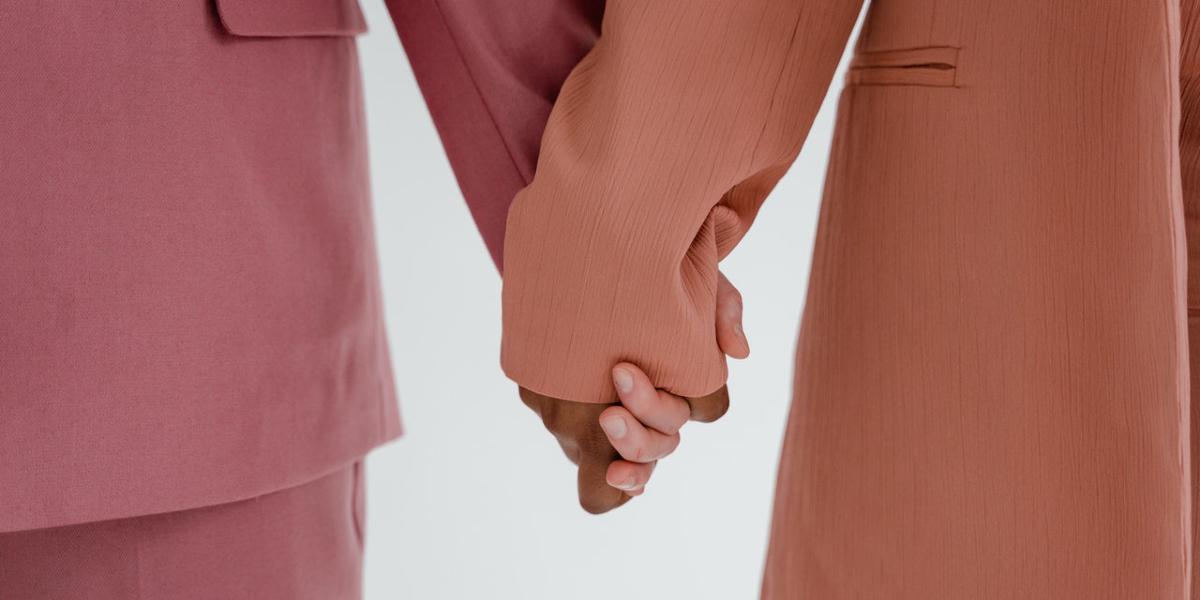 Main image Feminist Club Two woman in colourful suits holding hands.