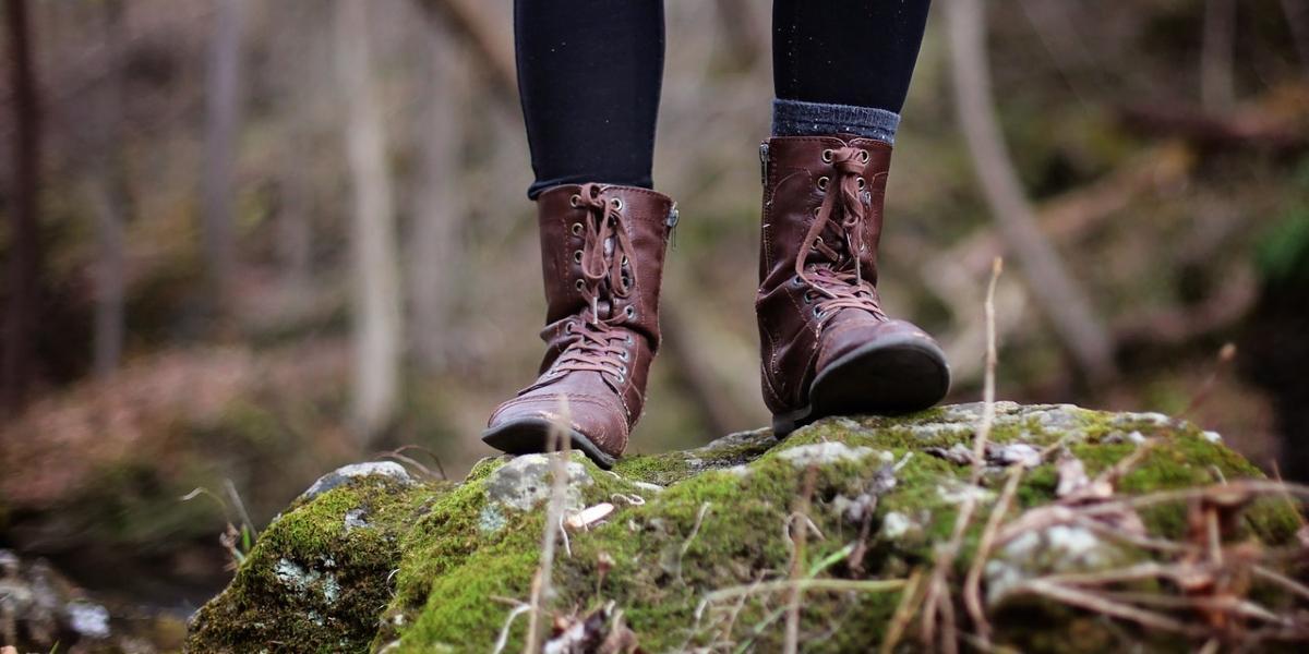 Close up of woman's feet stood on log in woodland.