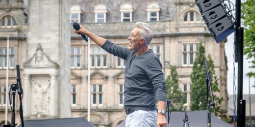 Page icon: Martin Kemp flag market Martin Kemp holding microphone out to crowd on Preston Flag Market.